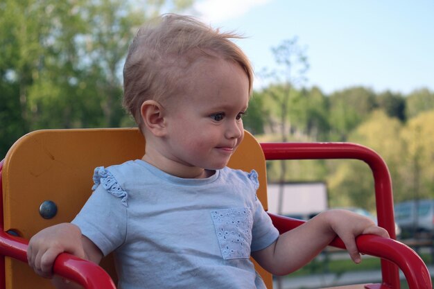 A little girl sits on a swing and smiles Closeup portrait