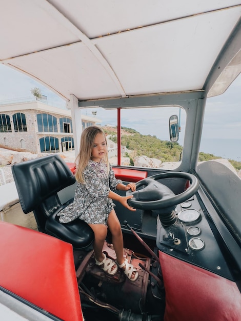 Foto la ragazzina si siede dietro il volante di un trattore nella cabina