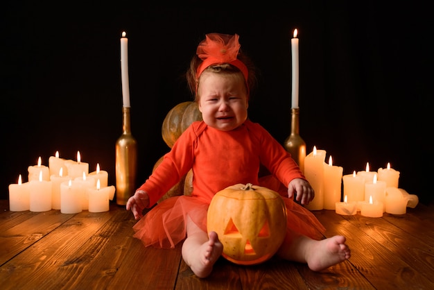 Little girl sits with jack pumpkins and candles