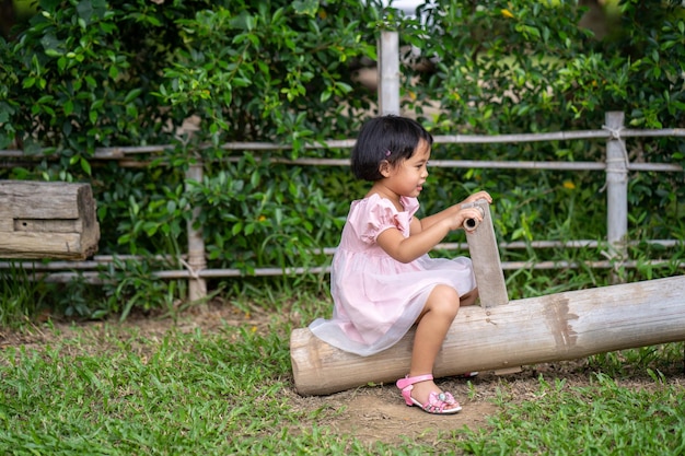 A little girl sits on a wooden boat in a garden.