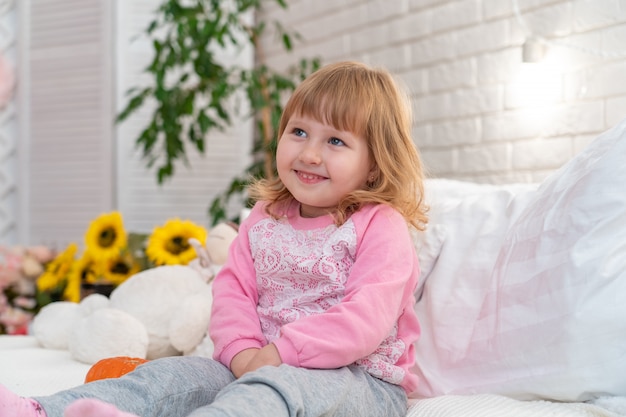 Little girl sitting on the bed at home