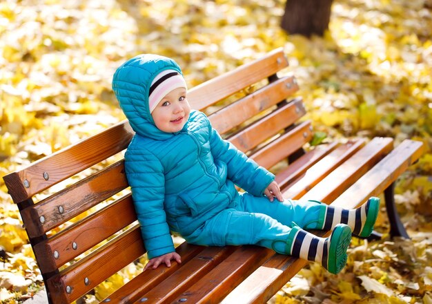 Маленькая девочка сидит на скамейке в парке