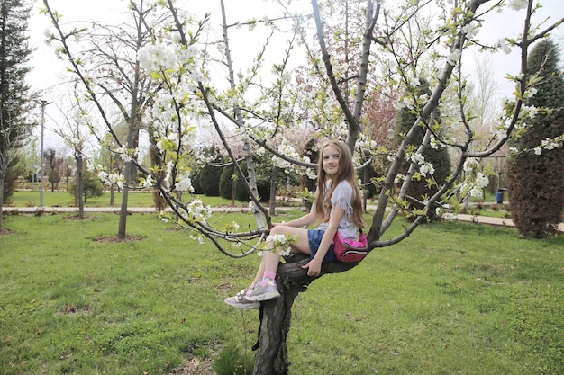 little girl sitting on a blossoming apple tre