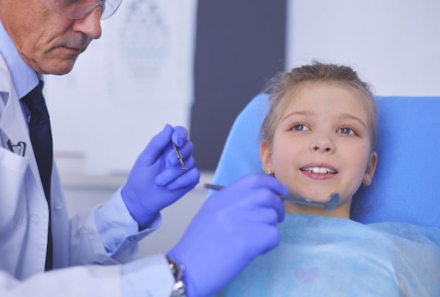 Маленькая девочка сидит в кабинете стоматолога