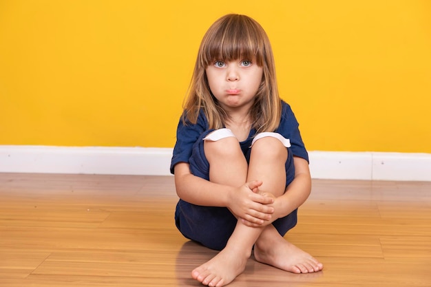 Bambina seduta sul pavimento con una benda sul ginocchio che simula un livido