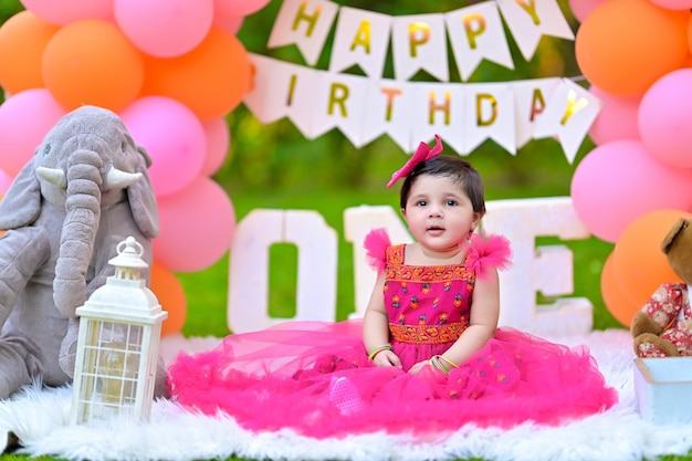 a little girl sitting in front of a sign that says happy birthday