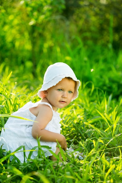 Little girl sitting in the green grass