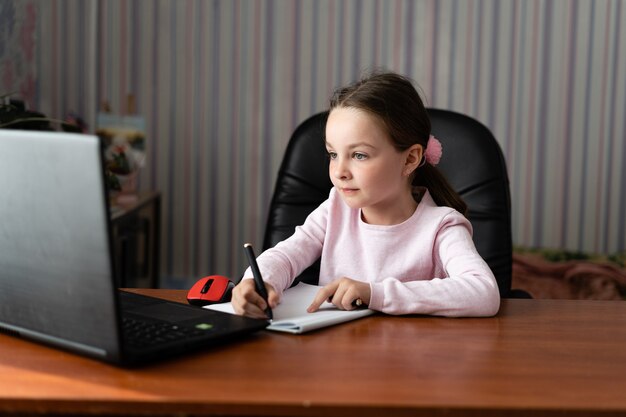 Little girl sitting at home holding a pen in her hands.