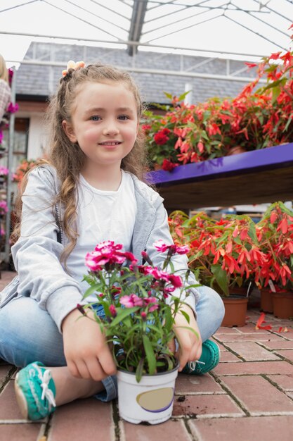 Little girl sitting on the path with a flower