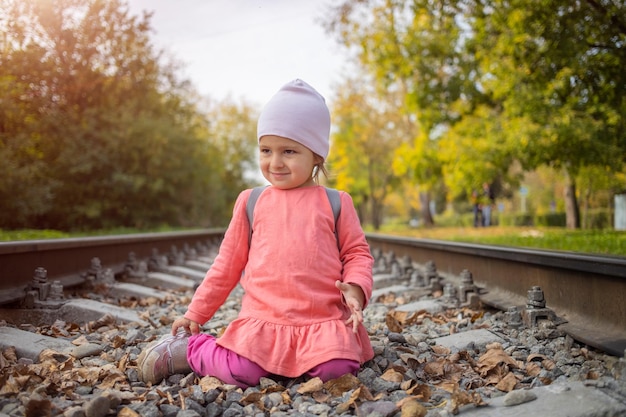 Little girl sitting on the railroad tracks