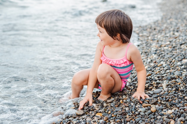 Little girl sitting at the seashore