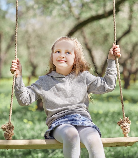 little girl sitting on a swing in the garden.