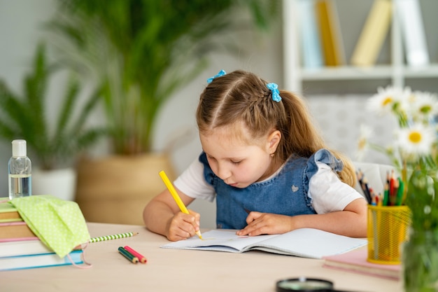 Little girl sitting at a table with a textbook