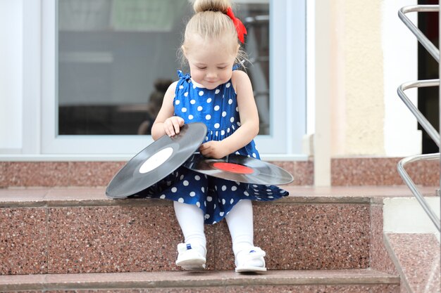 Little girl sitting with records on the steps