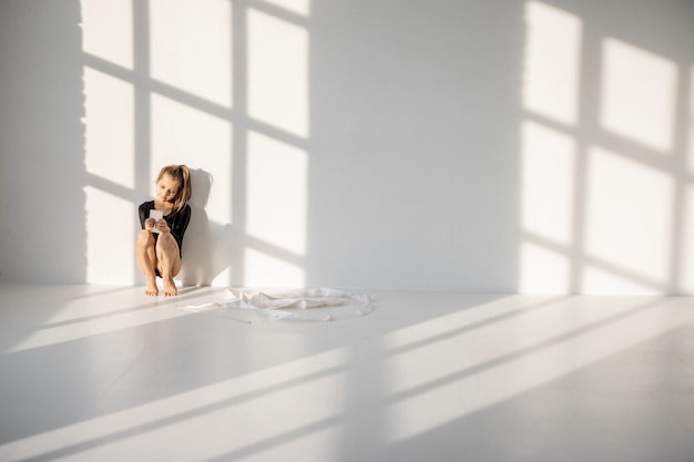 Little girl sitting with smart phone in gymnastics class