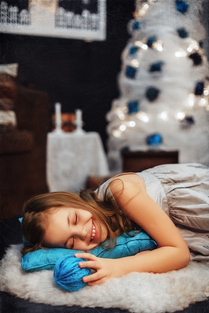 Little girl sleeping on a blue pillow. The concept of the New Year and Merry Christmas