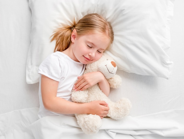 Little girl sleeping in white bed