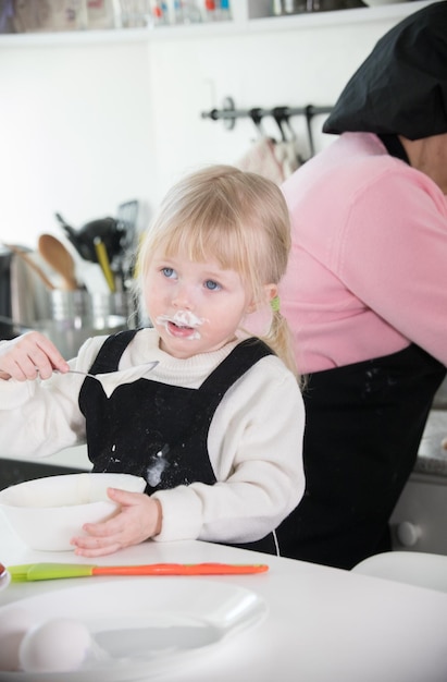 A little girl sloppy eating a sour cream in the kitchen