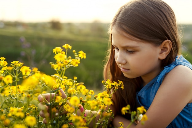 Little girl smelling a yellow flower