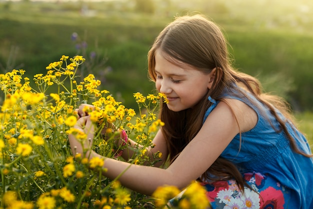 Little girl smelling a yellow flower