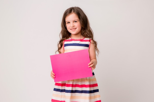 Little girl smiles and holds an empty pink paper