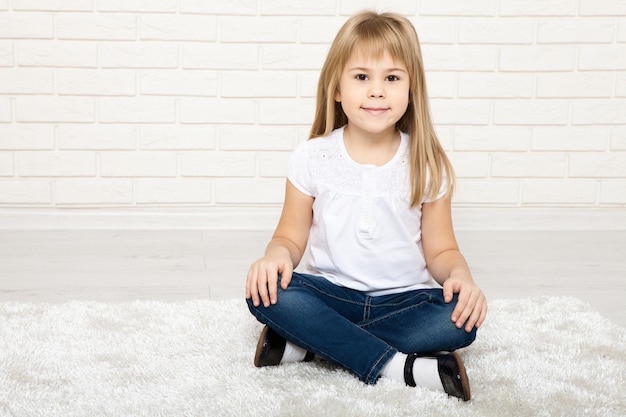 маленькая девочка улыбается и сидит на полу в комнате