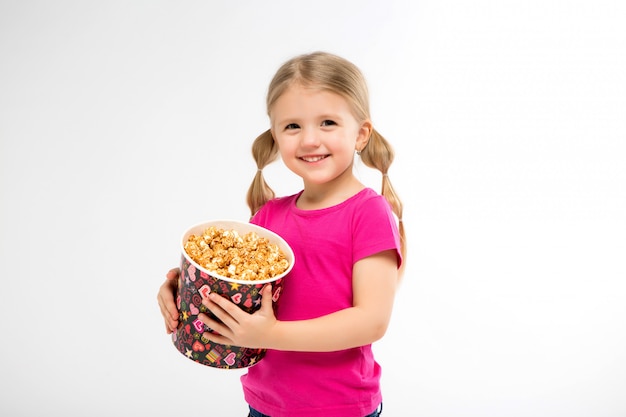 little girl smiles with a bucket of popcorn