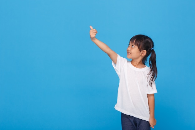 Little girl smiling doing ok sign on blue wall