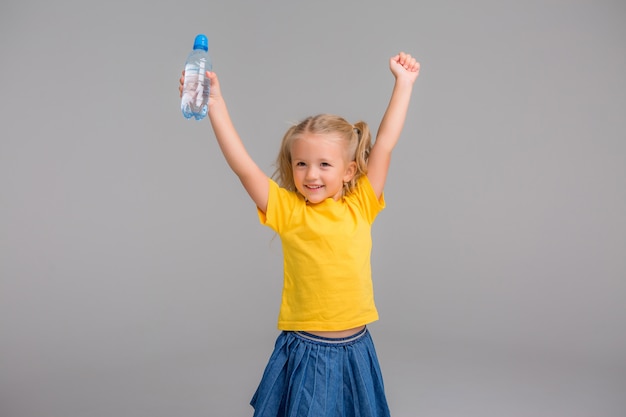 Bambina sorridente che tiene bottiglia d'acqua