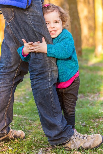 Little girl smiling and hugging dad's leg, family