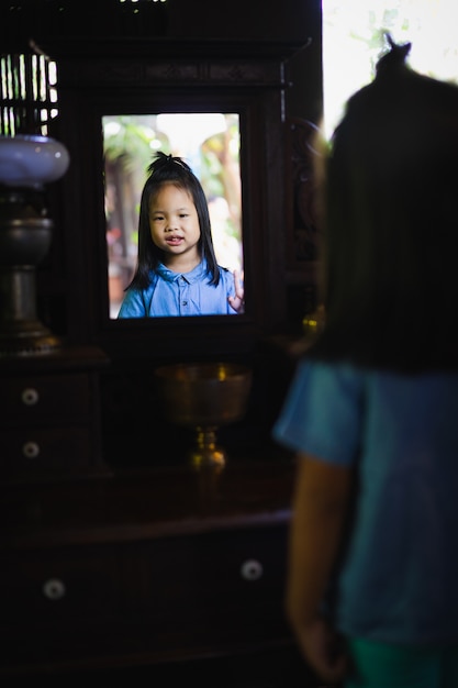 Little girl smiling and looking in the mirror