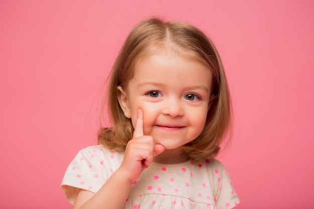 写真 ピンクの背景に笑みを浮かべて少女