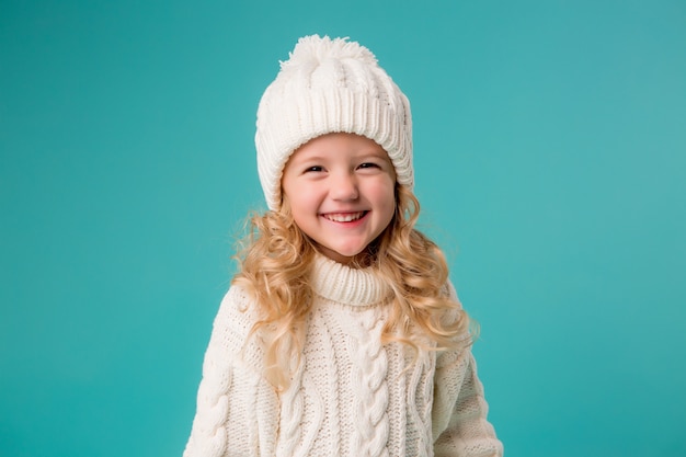 어린 소녀는 겨울 흰 모자와 스웨터에 웃 고 스케이트를 들고