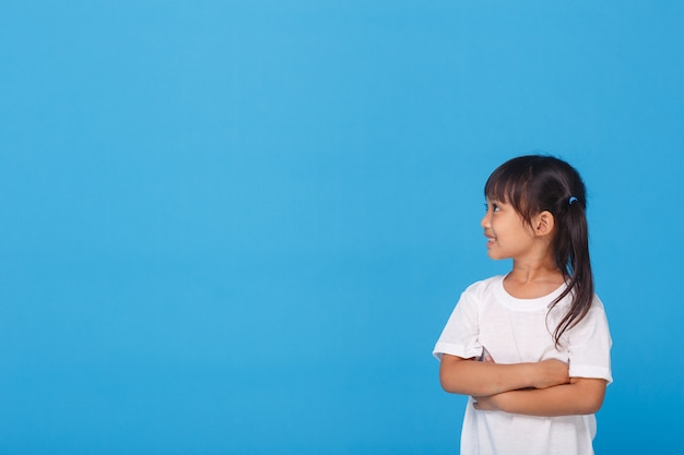 Little girl smiling with folded arms on blue wall