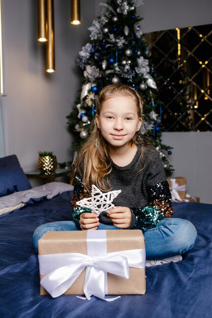 Little girl smiling with gift box near the Christmas tree. Christmas, holidays and childhood concept