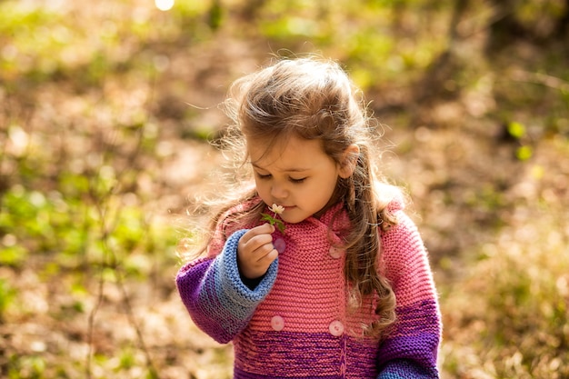 маленькая девочка нюхает цветок