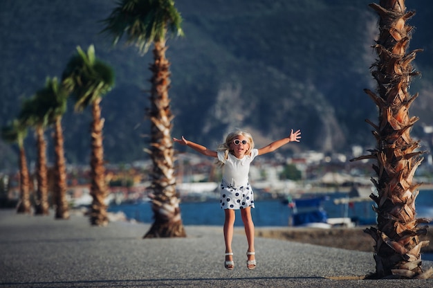 Little girl snuggles and plays in nature, against the backdrop of mountains and palm trees.