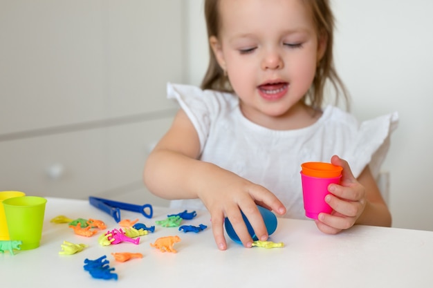 어린 소녀가 동물 모양을 색깔별로 분류하여 적절한 컵에 던집니다.