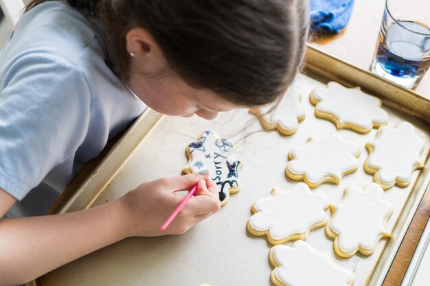 Photo little girl spells sorry on iced sugar cookies