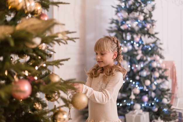 小さな女の子はクリスマスツリーを飾るのに時間を費やしています