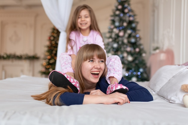 Little girl spends time playing with mom while lying in bed. Christmas tale. Happy childhood.