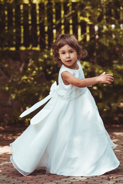 Photo little girl spinning around in ornate dress outdoor