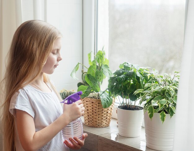 小さな女の子が観葉植物に水をはねかける