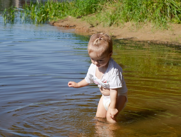 Photo little girl splashing in the water near the shore