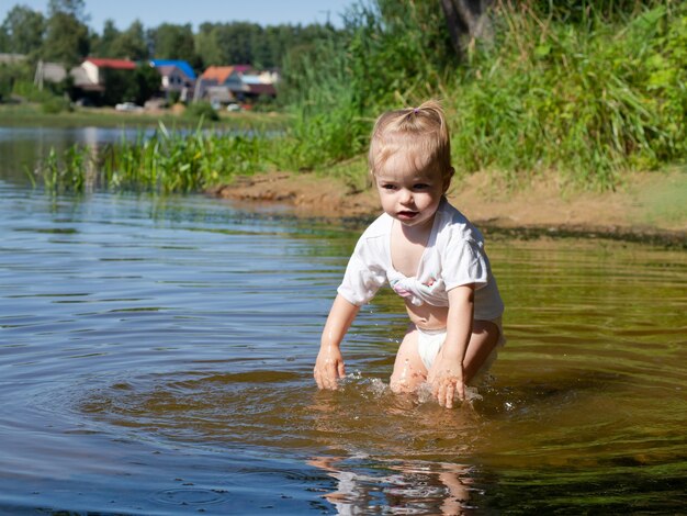 Маленькая девочка плещется в воде у берега