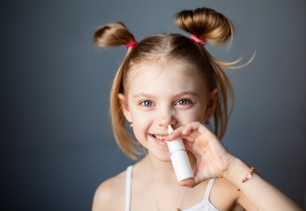 little girl sprinkles a nose spray