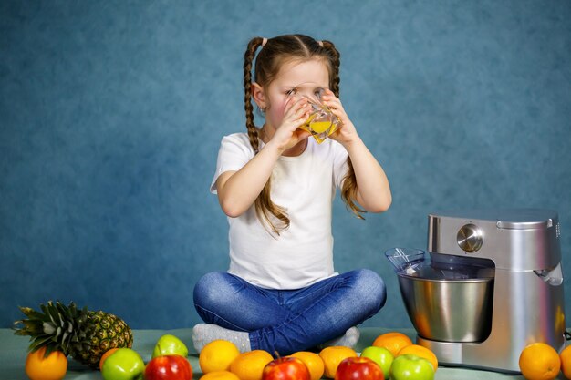 Little girl squeezed fresh juice from fruits of apples and orange. Vitamins and healthy nutrition for children.