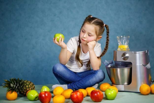 Little girl squeezed fresh juice from fruits of apples and orange. Vitamins and healthy nutrition for children.