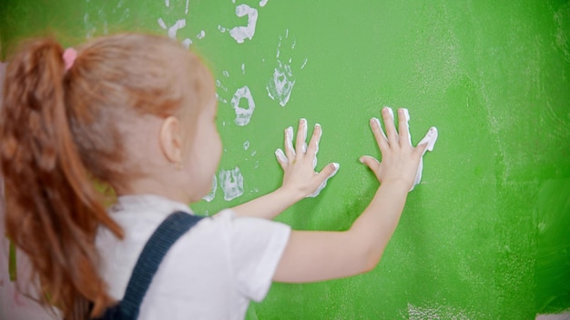 A little girl stamping her handprints on the wall