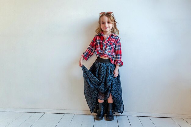 Little girl standing against white wall background in bright room